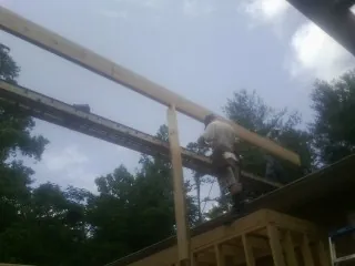Carpenter setting a ridge beam over a new addition frame — Ice Dam Removal by Roofing Brothers in Des Moines