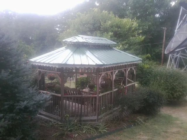 Green metal roof on a backyard gazebo surrounded by garden beds in Des Moines