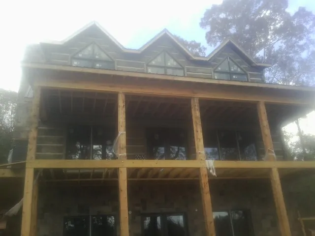 Dormers and porch framing on a large log home under construction — Roof Coating work by our crew in Des Moines