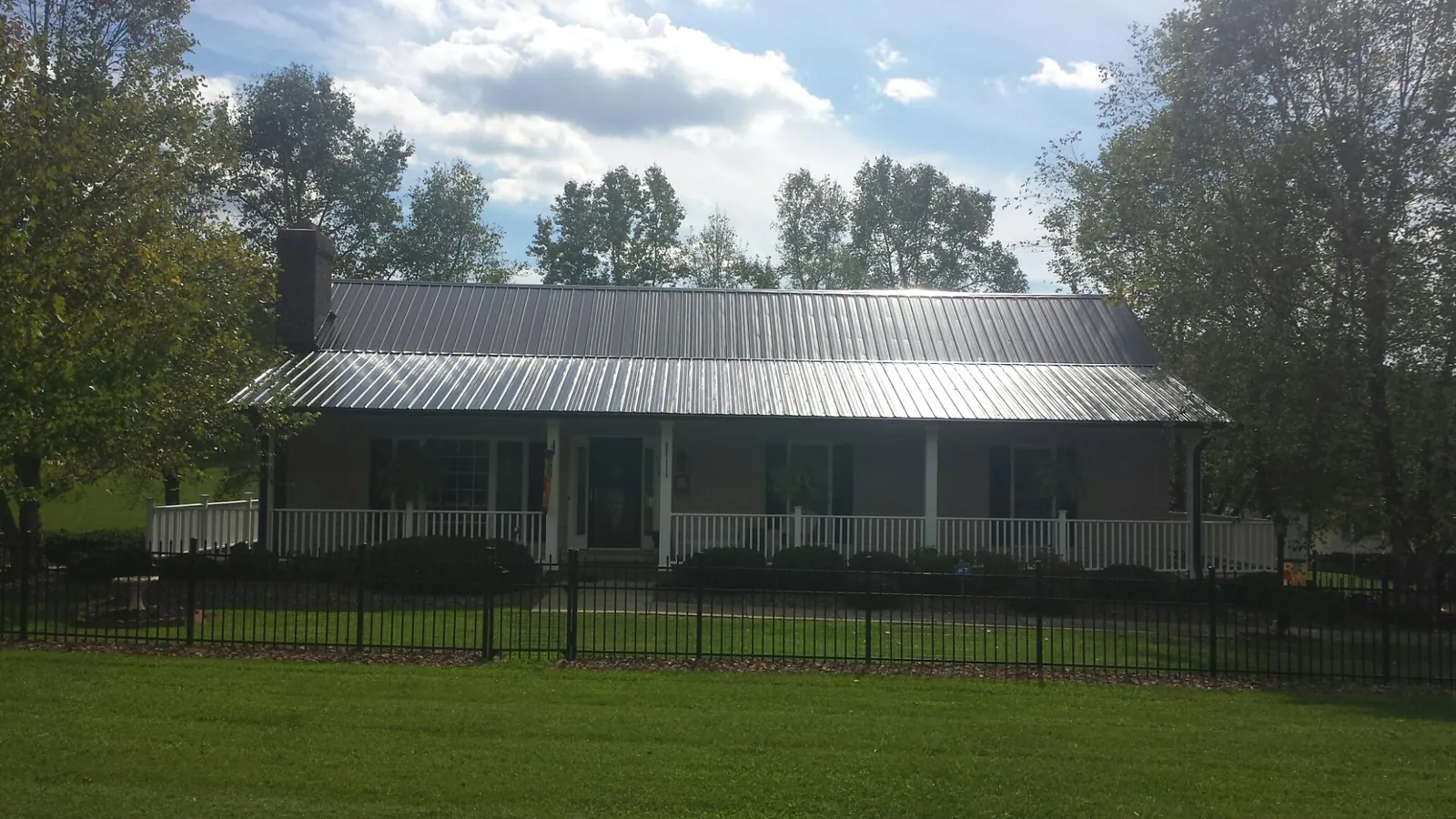 Gray metal roof on a brick ranch with a full width front porch — Gutter Guard Installation work by our crew in Des Moines