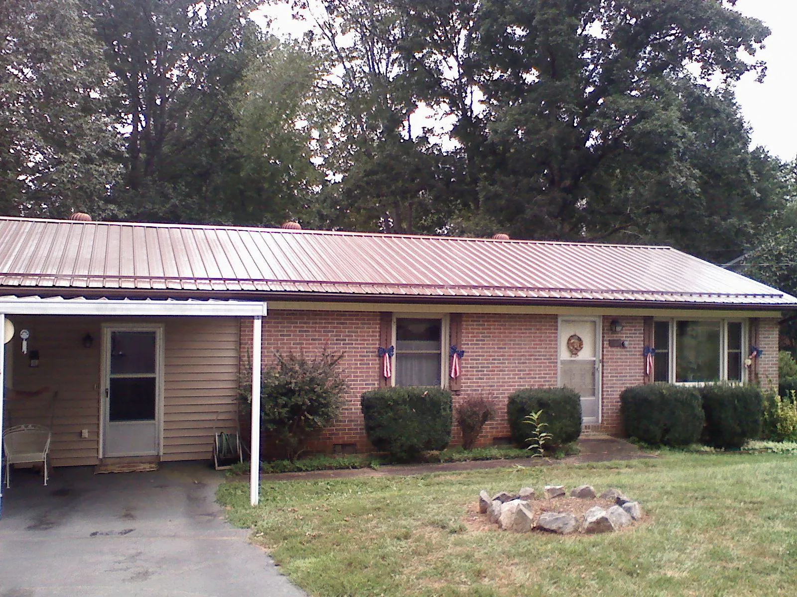 Bronze metal roof and carport on a brick ranch home — Roof Repair work by our crew in Des Moines